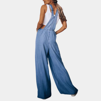 Femme portant une salopette en jean bleu clair, style décontracté, avec un débardeur blanc. Mode féminine, tenue estivale tendance.