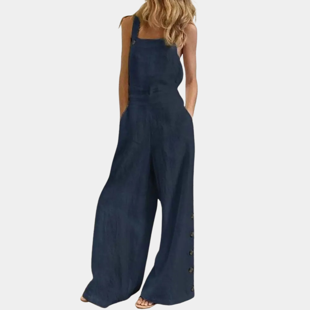 Combinaison femme en jean bleu foncé, style décontracté, jambes larges, bretelles, boutons latéraux, mode tendance, tenue estivale élégante.