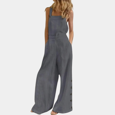 Combinaison femme ample en lin gris, sans manches, avec boutons latéraux, poches, et coupe décontractée. Mode estivale élégante et confortable.