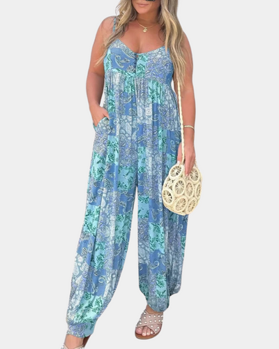 Femme portant une combinaison bleue à motifs floraux, tenant un sac rond en osier. Mode estivale, tenue décontractée, style bohème chic.