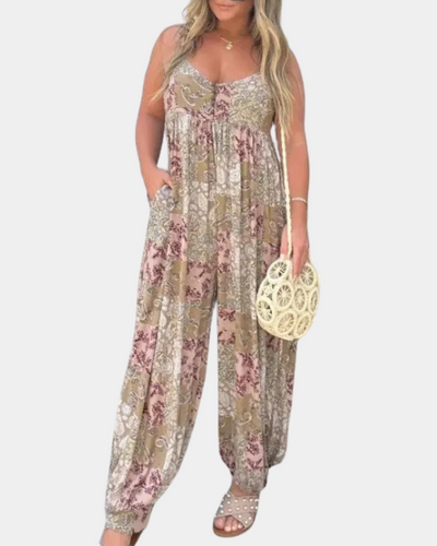 Combinaison femme bohème chic à motifs floraux, tons beige et rose, avec poches. Accessoirisée d'un sac rond en osier et sandales cloutées.