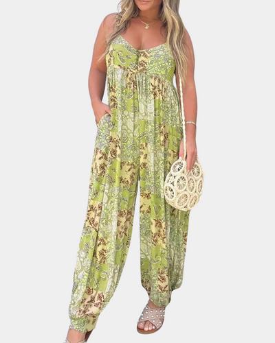 Combinaison femme bohème verte à motifs floraux, tenue estivale décontractée, accessoirisée d'un sac rond en osier et sandales cloutées.