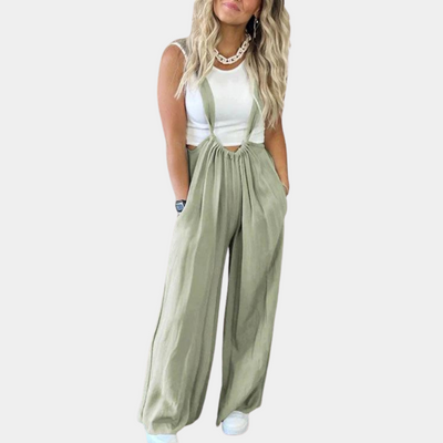 Femme portant une salopette verte ample avec un débardeur blanc, collier tendance et baskets blanches. Mode décontractée chic pour femme.