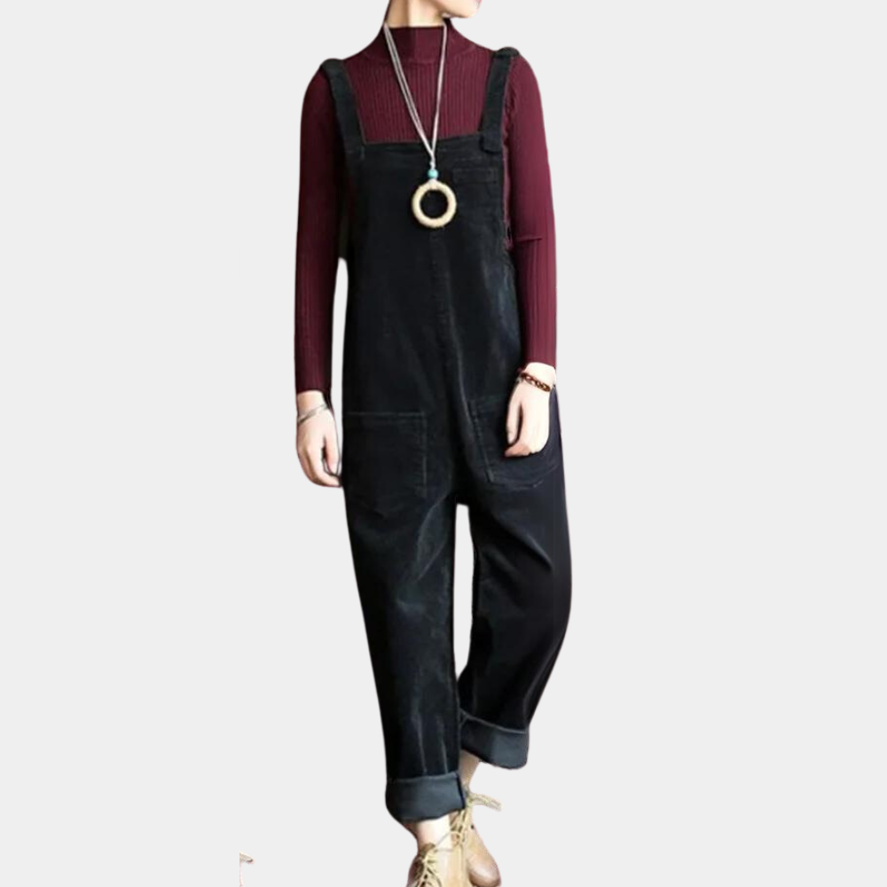 Combinaison noire en velours côtelé, portée avec un pull bordeaux à manches longues et un collier pendentif, style décontracté et moderne.