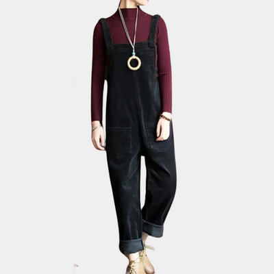 Combinaison noire en velours côtelé, portée avec un pull bordeaux à manches longues et un collier pendentif, style décontracté et moderne.