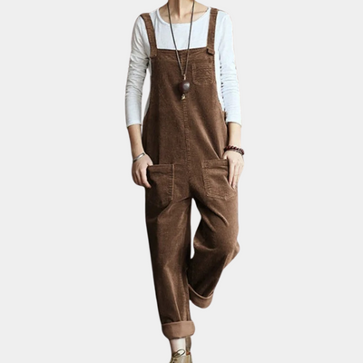 Salopette en velours côtelé marron pour femme, style décontracté, avec poches avant, portée sur un t-shirt blanc à manches longues. Mode automne-hiver.