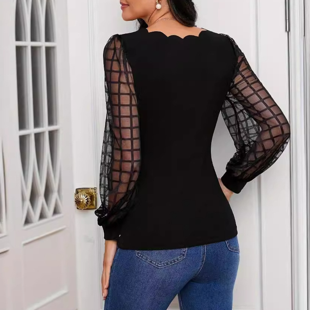 Femme portant un haut noir élégant avec manches en maille transparente et jeans bleus, posant de dos devant une porte blanche. Mode chic et moderne.