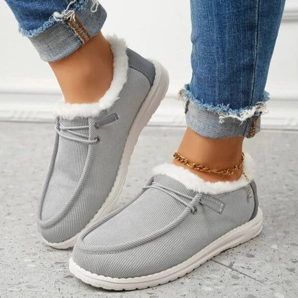 Chaussures mocassins gris en tissu côtelé avec doublure en fourrure blanche, portées avec un jean décontracté. Mode automne-hiver, confort et style.