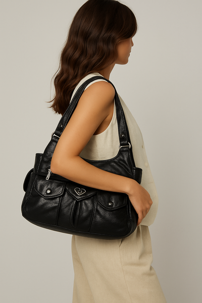Femme portant un sac à main en cuir noir élégant, design moderne, poches avant, tenue beige. Accessoire mode tendance, style chic et pratique.