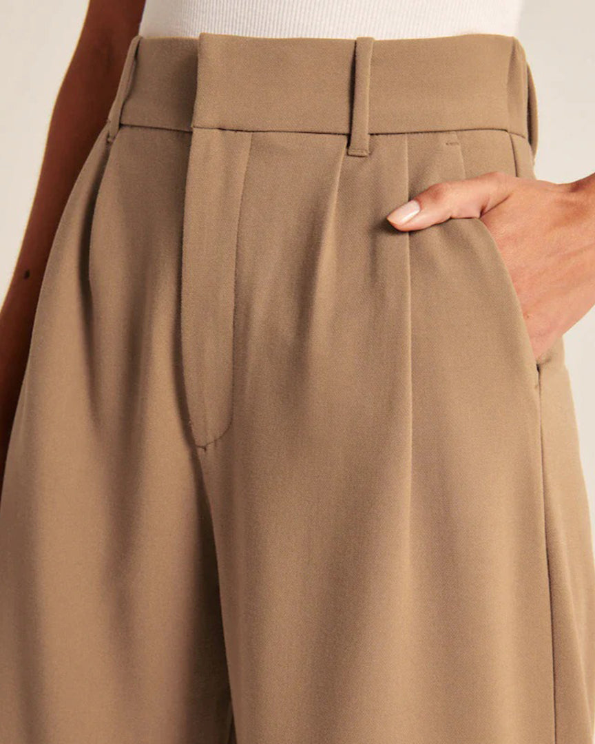 Pantalon beige taille haute pour femme, coupe ample, avec poches latérales, tissu léger et élégant, parfait pour un look chic et décontracté.