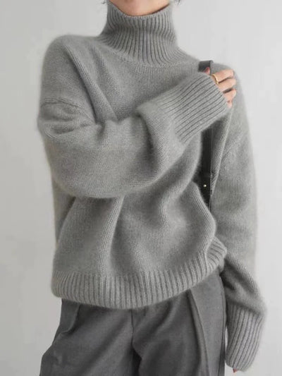Pull gris en laine à col roulé, manches longues, porté par une personne. Style décontracté et élégant, idéal pour l'hiver. Mode automne-hiver tendance.