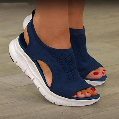 Sandales bleues confortables pour femmes avec semelle blanche, design ouvert, portées sur un sol en bois. Chaussures d'été tendance et ergonomiques.