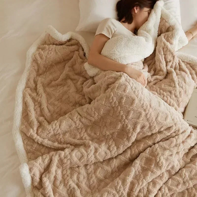 Femme dormant sous une couverture en peluche beige sur un lit, tenant un oreiller blanc. Confort, sommeil, literie douce et cosy.