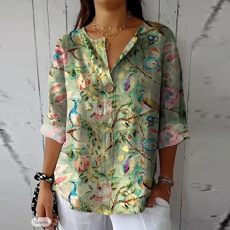 Blouse femme à motifs floraux et paons, manches longues retroussées, fond vert pastel, col en V, boutons, style décontracté et élégant.