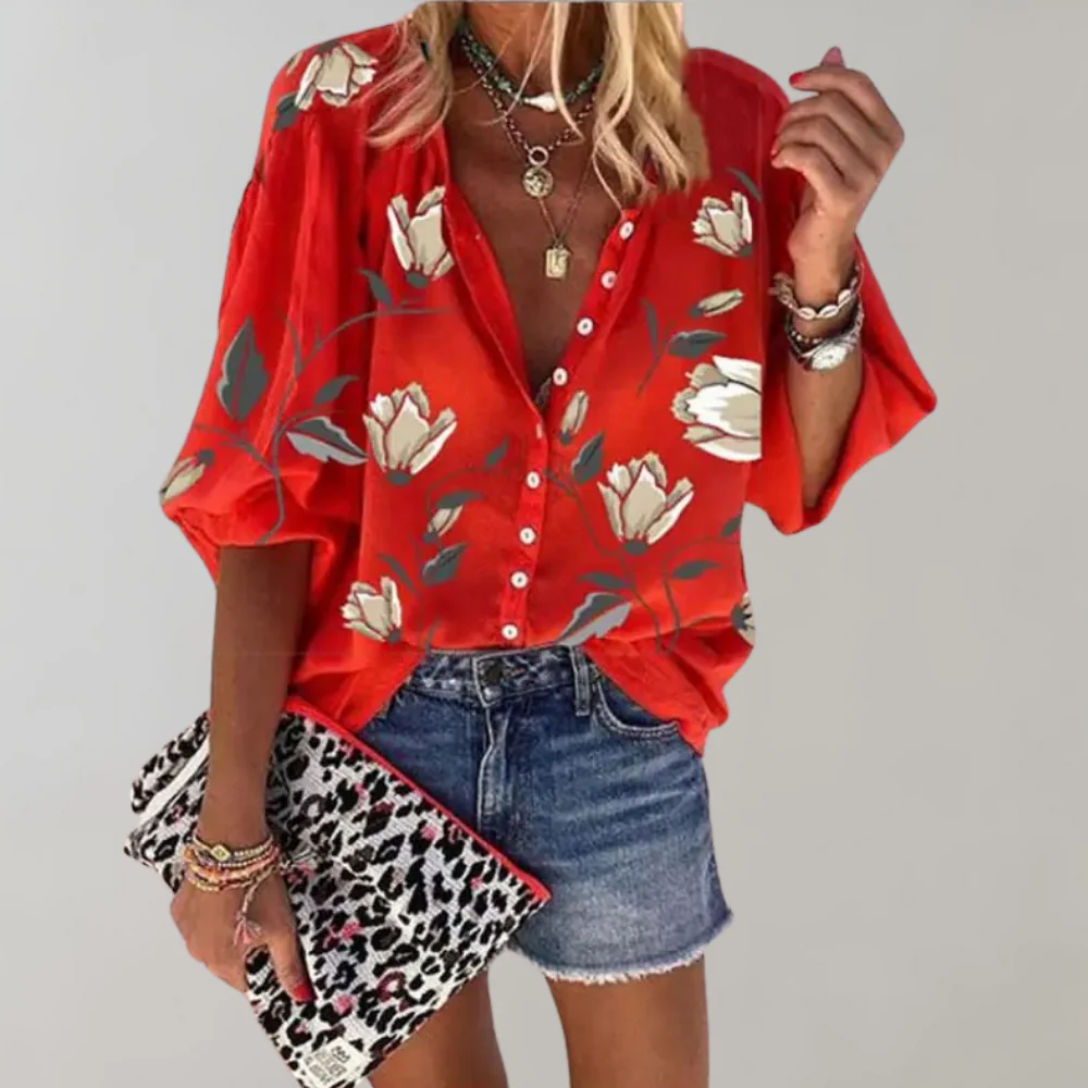 Blouse rouge à fleurs blanches, manches amples, portée avec short en jean. Accessoires: collier, bracelets, pochette léopard. Mode estivale chic.