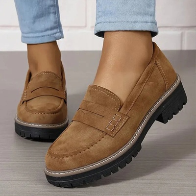 Chaussures mocassins marron en daim pour femme, semelle épaisse noire, portées avec un jean bleu clair. Mode automne, confort et style décontracté.