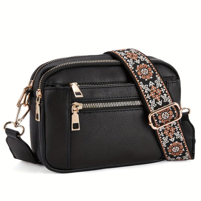 Sac à bandoulière noir en cuir avec sangle brodée florale, fermetures éclair dorées. Accessoire mode élégant et pratique pour femme.