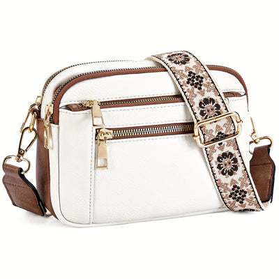 Sac à bandoulière blanc en cuir avec détails marron, fermeture éclair dorée et sangle florale ajustable. Accessoire mode élégant et tendance.