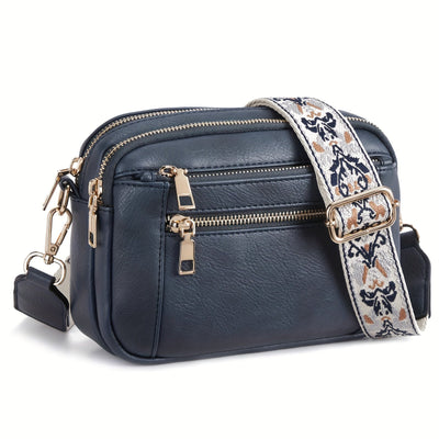 Sac bandoulière en cuir bleu avec fermetures éclair dorées et sangle brodée. Accessoire mode élégant et pratique pour femme.
