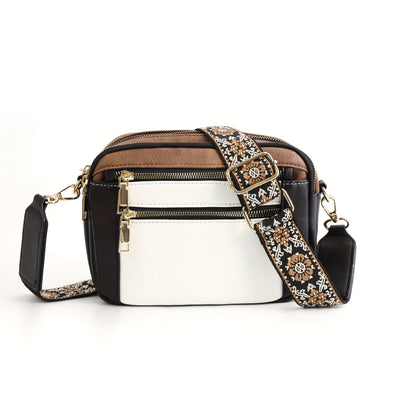 Sac à bandoulière en cuir noir et blanc avec sangle brodée florale, fermetures éclair dorées, design élégant et moderne pour femme.