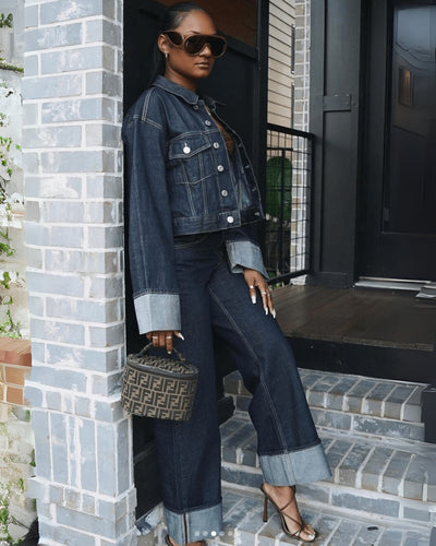 Femme en tenue denim, veste et pantalon, posant sur des marches. Porte des lunettes de soleil et un sac à main Fendi. Mode urbaine chic.