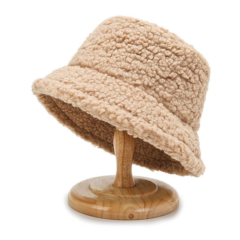 Chapeau bob en laine bouclée beige sur support en bois, accessoire de mode tendance automne-hiver, style décontracté et élégant.