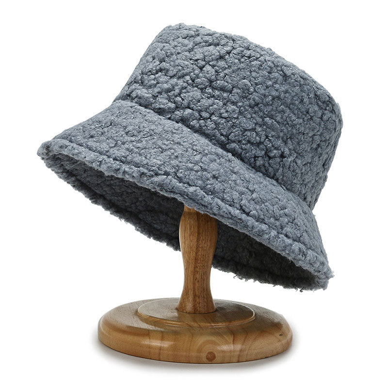 Chapeau bob en laine bouclée grise sur support en bois, accessoire de mode tendance, style hiver, texture douce et chaude.