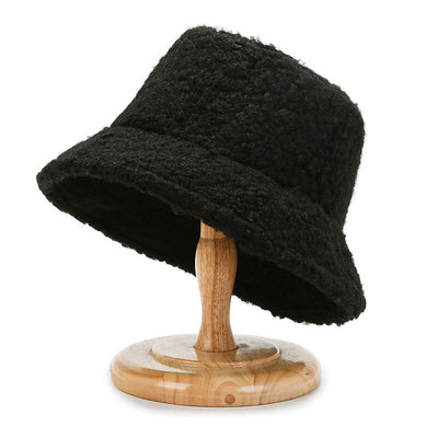 Chapeau bob en laine bouclée noire sur support en bois, accessoire de mode tendance, style automne-hiver, élégant et confortable.