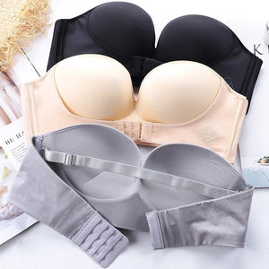 Soutiens-gorge sans bretelles noir, beige et gris, avec fermeture à agrafes, posés sur une surface blanche. Lingerie féminine élégante et confortable.