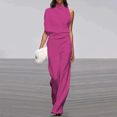 Robe longue fuchsia élégante, sans manches, avec pochette blanche, portée par un mannequin sur un podium de défilé de mode.