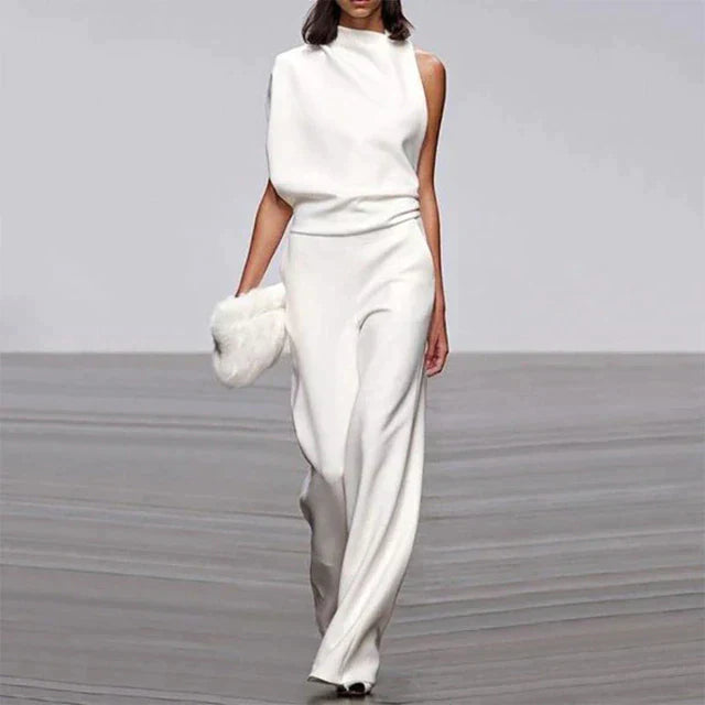 Femme défilant en tenue blanche élégante, combinaison asymétrique, accessoire en fourrure, mode haute couture, podium, style moderne.