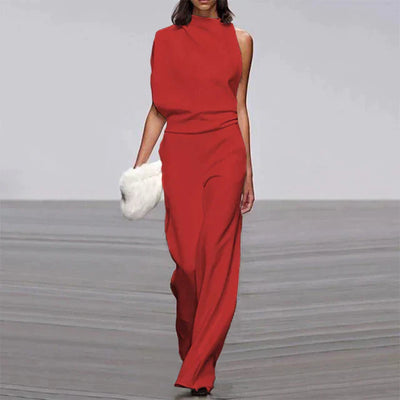 Robe rouge asymétrique élégante sur mannequin, accessoirisée d'une pochette blanche, défilé de mode, style moderne et chic.