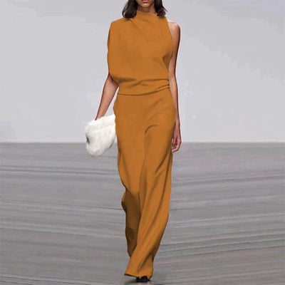 Robe asymétrique orange élégante sur mannequin, accessoirisée d'une pochette blanche, défilé de mode, style moderne et chic.