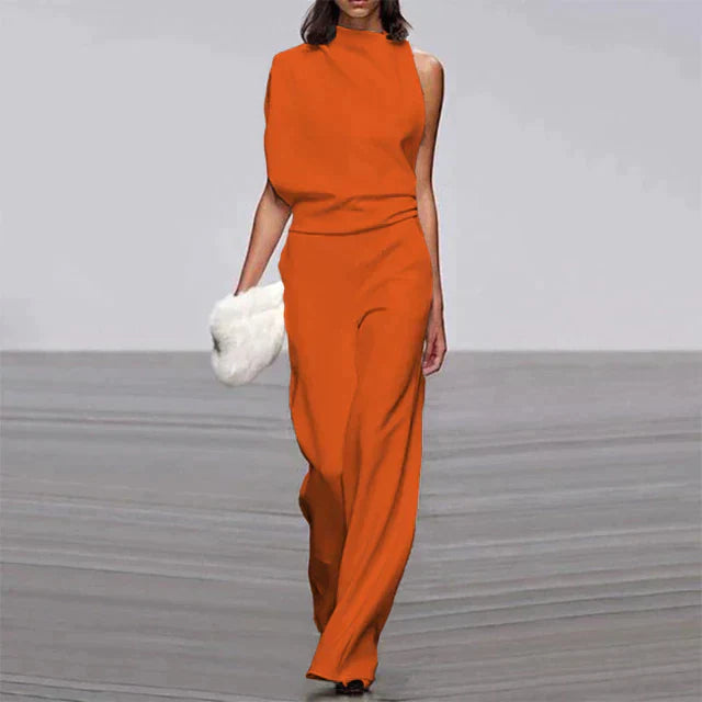 Robe orange asymétrique élégante, portée par une femme tenant une pochette blanche, défilé de mode, style moderne et chic.