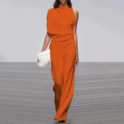 Robe orange asymétrique élégante, portée par une femme tenant une pochette blanche, défilé de mode, style moderne et chic.