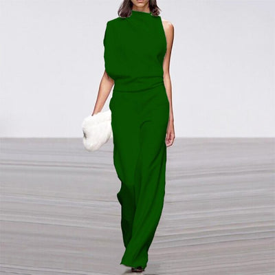 Personne portant une élégante combinaison verte asymétrique, tenant une pochette blanche. Mode féminine, style moderne, tenue de soirée chic.