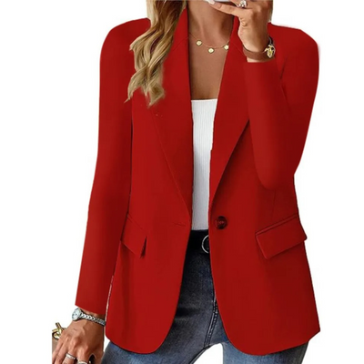 Femme portant un blazer rouge élégant, chemise blanche, jean bleu, accessoires dorés. Mode féminine chic, tenue professionnelle moderne.