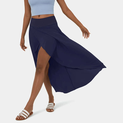 Femme portant une jupe longue bleue avec fente, top bleu clair et sandales blanches. Mode estivale élégante et décontractée.