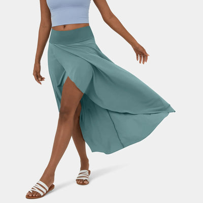 Femme portant une jupe longue bleue avec fente, top court bleu clair et sandales blanches. Mode estivale élégante et décontractée.