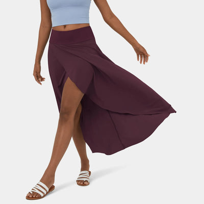 Femme portant une jupe longue violette avec fente, top bleu clair, sandales blanches. Mode estivale élégante et décontractée.