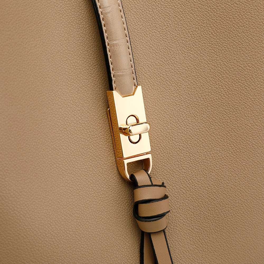 Gros plan sur un sac à main en cuir beige avec fermoir doré élégant et lanière en cuir. Accessoire de mode chic et tendance pour femmes.