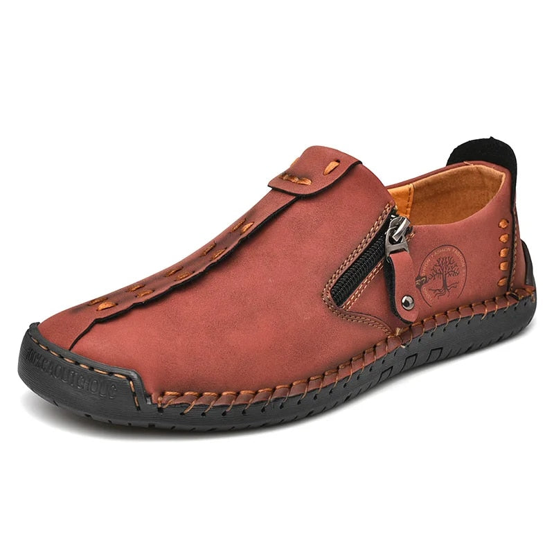 Chaussure en cuir marron pour homme avec fermeture éclair latérale, semelle noire antidérapante, coutures apparentes, style décontracté et confortable.