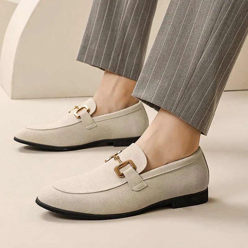 Chaussures mocassins beiges élégantes avec boucle dorée, portées avec un pantalon gris à rayures. Mode homme, style chic et moderne.