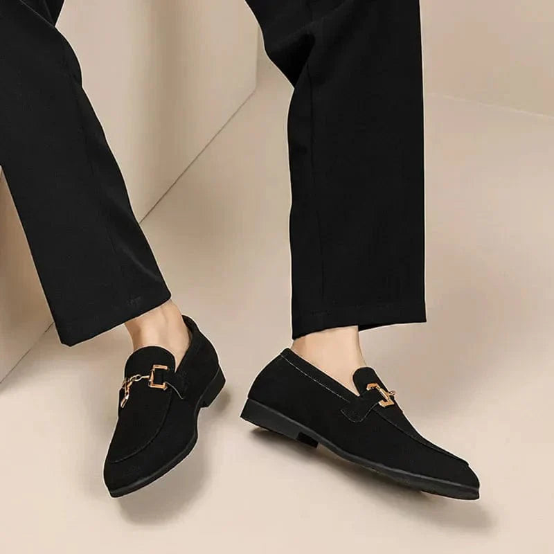 Chaussures mocassins noirs élégants pour homme, avec boucle dorée, portés avec un pantalon noir. Style moderne et chic. Mode masculine tendance.