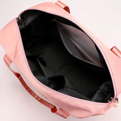 Sac de voyage rose ouvert avec intérieur noir, compartiments multiples et poignées robustes. Idéal pour le rangement et les voyages.