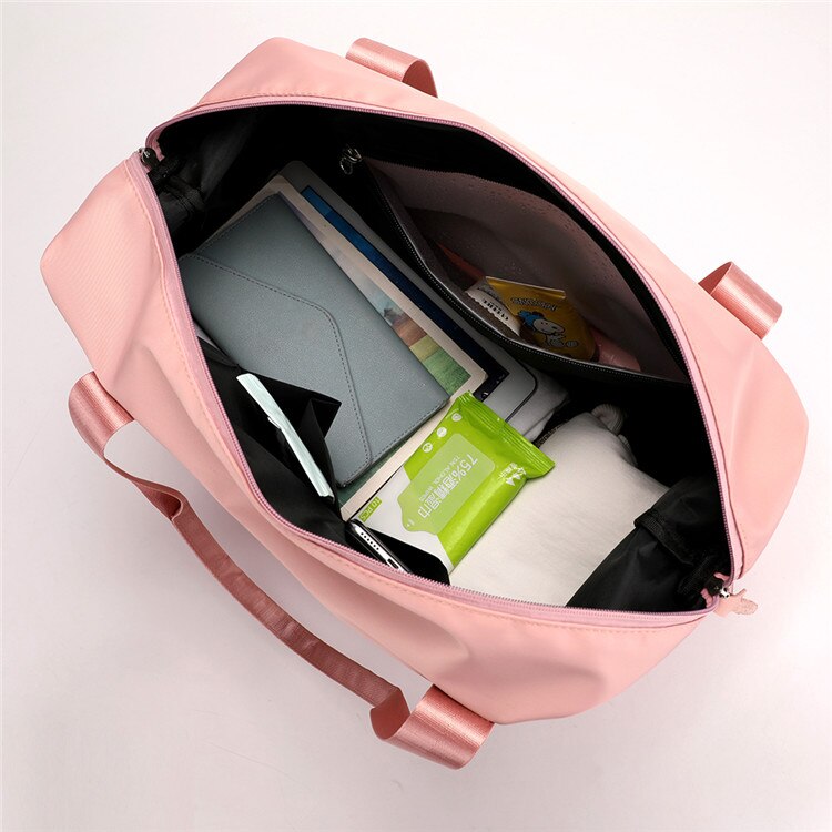 Sac à main rose ouvert avec tablette, carnet, mouchoirs et vêtements à l'intérieur. Accessoire de mode pratique pour le quotidien.