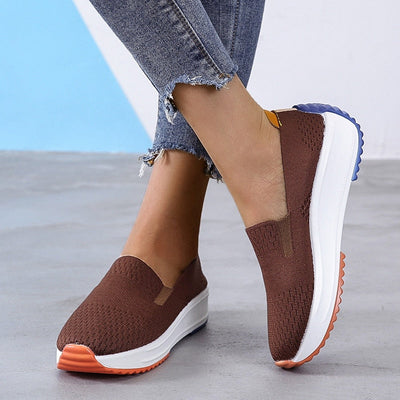 Chaussures marron en maille pour femme, semelle blanche épaisse, détails orange et bleu, portées avec un jean décontracté. Mode confortable et tendance.