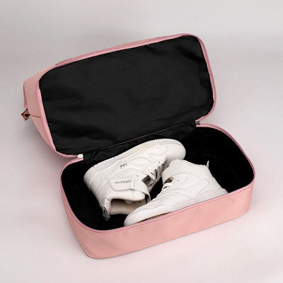 Chaussures de sport blanches dans un sac de rangement rose ouvert. Accessoire de voyage pratique pour organiser et protéger les baskets.