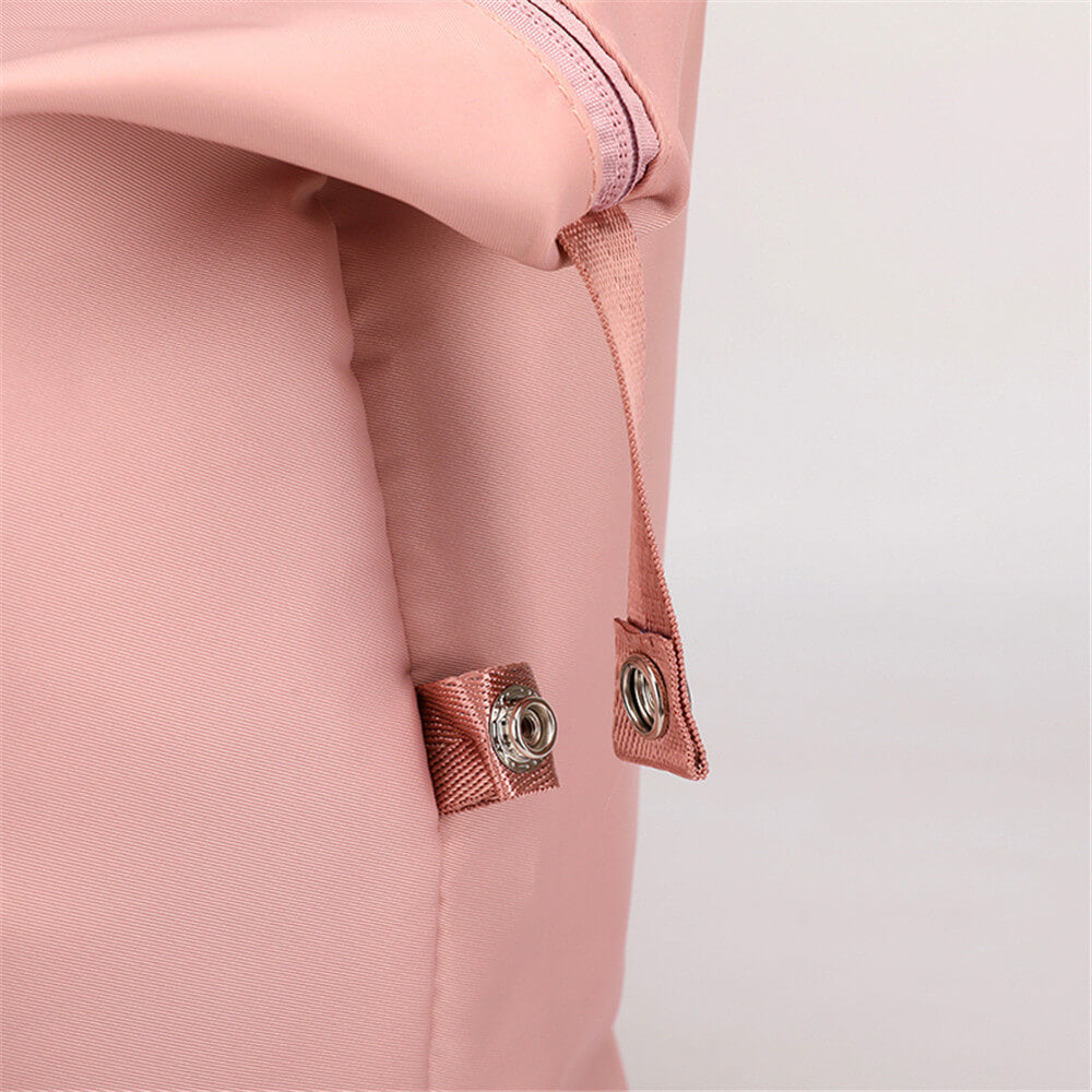 Sac à dos rose en tissu imperméable avec fermeture éclair robuste et bouton-pression. Design moderne et pratique pour usage quotidien.