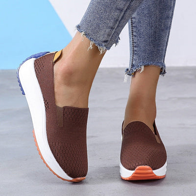 Chaussures marron en maille pour femme, semelle épaisse blanche, détails orange et bleu, portées avec un jean déchiré. Confort et style décontracté.